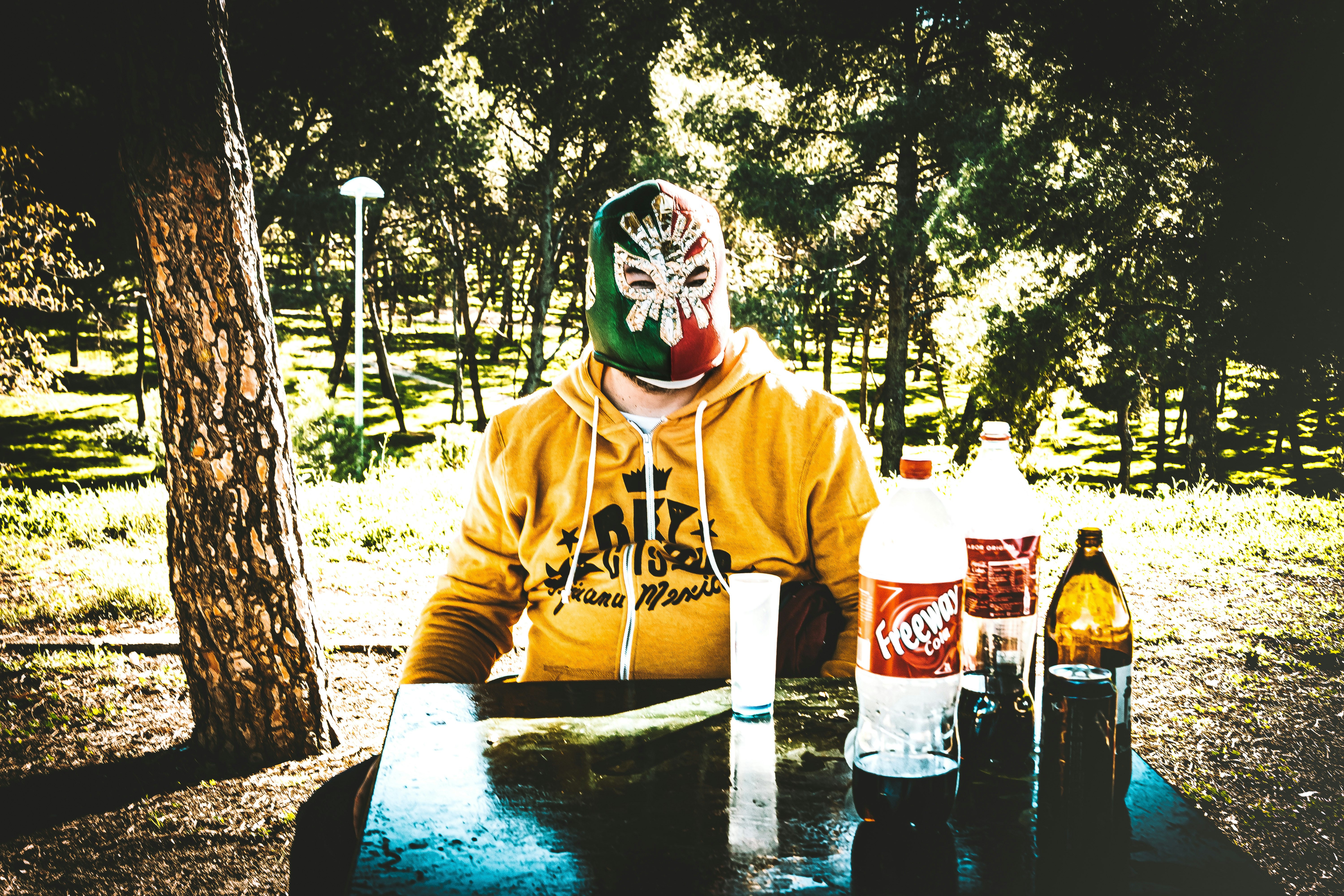 person in yellow hoodie wearing mask and mask holding coca cola bottle